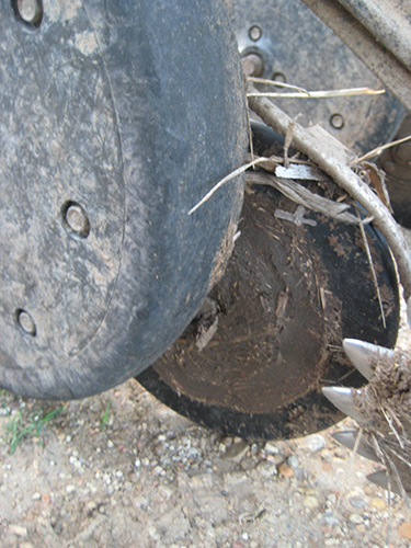 Competitor seed lock wheel clogged with mud and dragging against gauge wheel.