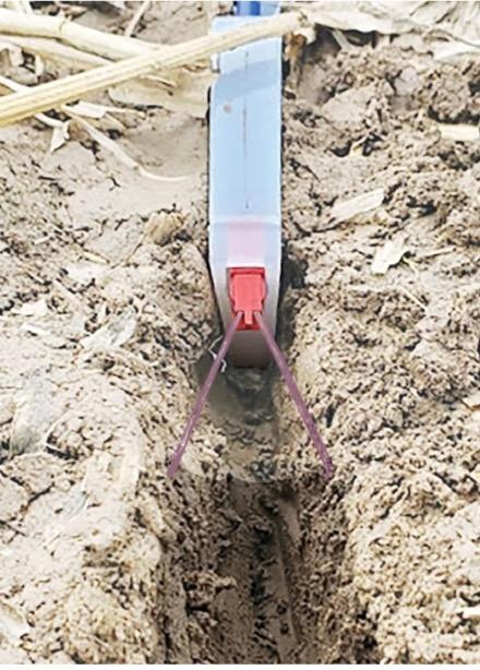 Keeton Seed Firmer in a furrow in the field.